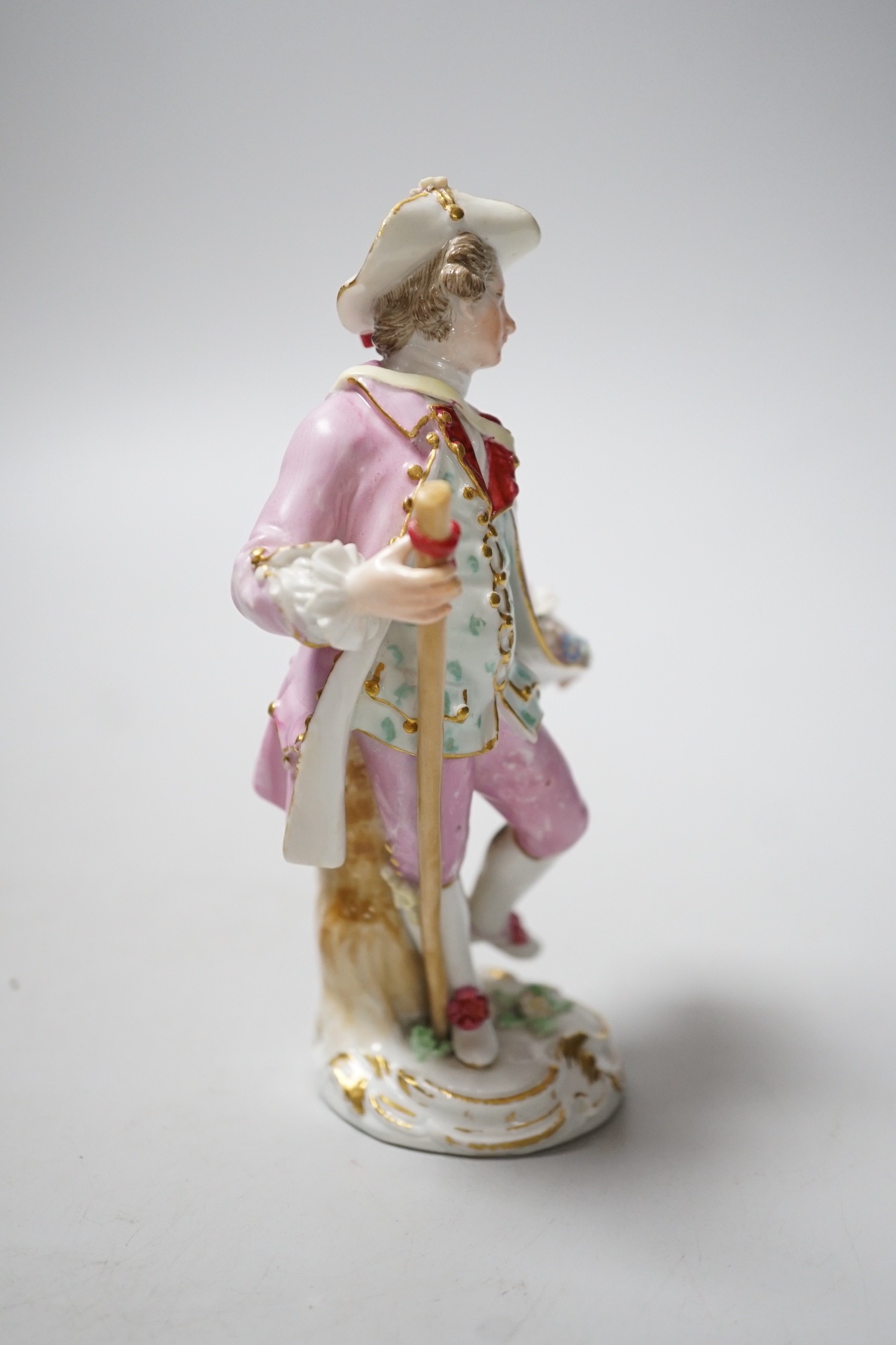A Meissen figure of a young man with walking stick and his tail full of flowers, late 18th century, blue crossed swords to back of base